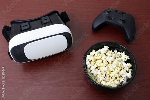 Photos Virtual reality headset goggles sitting next to bowl of popcorn and generic remo