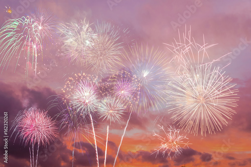 Beautiful colorful holiday fireworks in the sunset/evening sky with majestic clouds, long exposure. Concept of American Independence celebration. Happy Independence Day or Fourth of July banner.