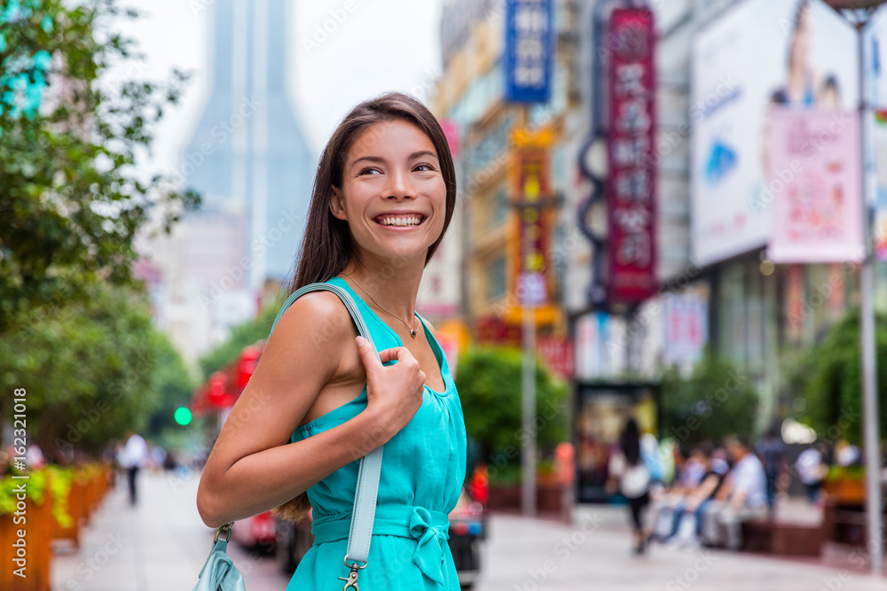 Obraz premium Chinka na zakupy w mieście Nanjing Road Szanghaj, Chiny. Szczęśliwa dziewczyna spaceru jednym z najbardziej ruchliwych deptaków na świecie. Azjatyckie kobiety turystyczne odwiedzające sklepy. Słynny punkt orientacyjny chińskiej atrakcji.