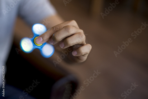 Young man playing with a fidget spinner with light