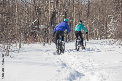 Attractive couple riding fat bikes in the snow