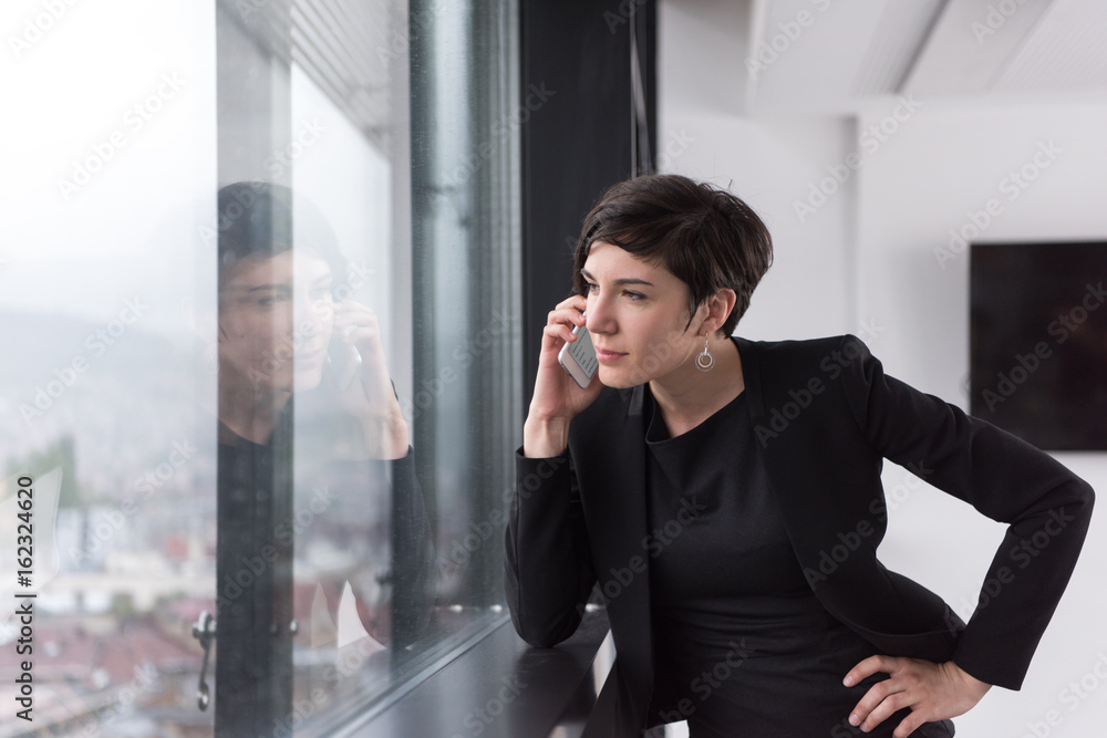 Elegant Woman Using Mobile Phone by window in office building Elegant Woman Using Mobile Phone by window in office building