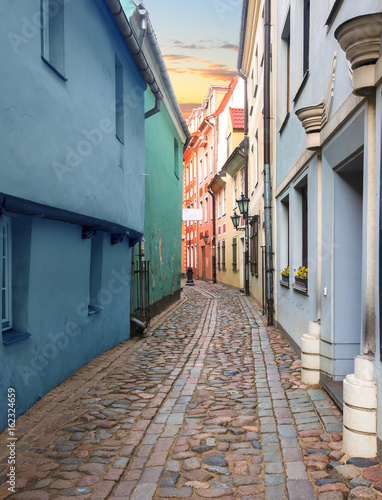 Narrow street in old Riga - the capital of Latvia and famous tourist city in Baltic region where everyone can feel unforgettable atmosphere of Middle Ages and unique Gothic architecture © sergei_fish13