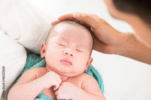 Father touching head of sleeping baby with care