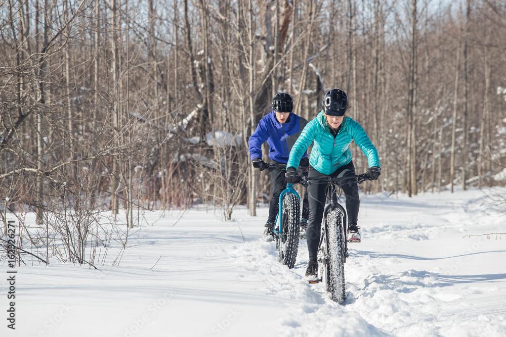 Attractive couple riding fat bikes in the snow