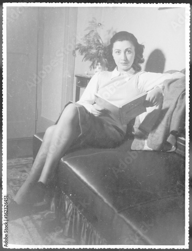 Photos Woman Reads on Sofa. Date: 1940s