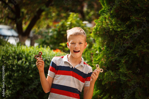 Bild auf Leinwand Teenager playing with fidget hand spinners in summer day