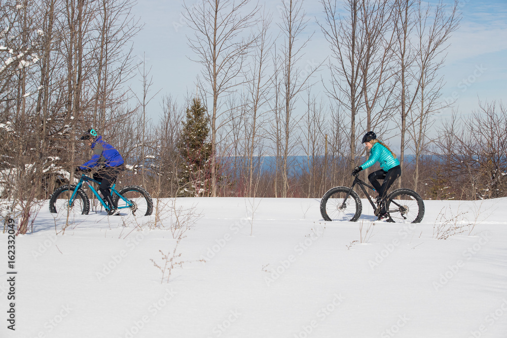 Attractive couple riding fat bikes in the snow