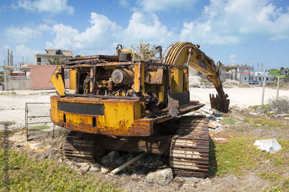 Abandoned excavator outside the city on a sunny day. Fully damaged metal and motor. Rusty surface, ecological waste on the ground. Abandoned excavator outside the city on a sunny day. Fully damaged metal and motor. Rusty surface, ecological waste on the ground.
