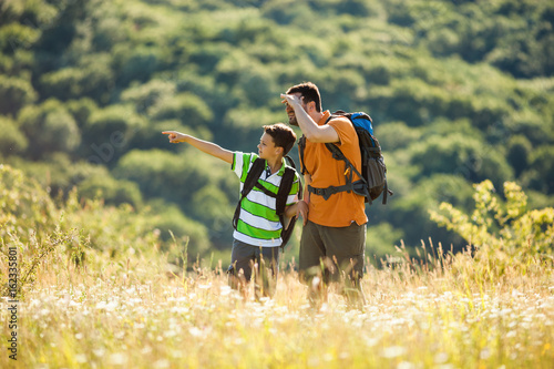Father and son are hiking in nature in summer.