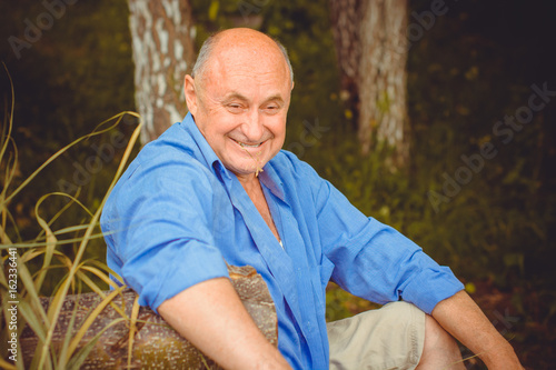 Fototapeta Naklejka Na Ścianę i Meble -  Portrait happy mature man in blue shirt and casual style on a nature
