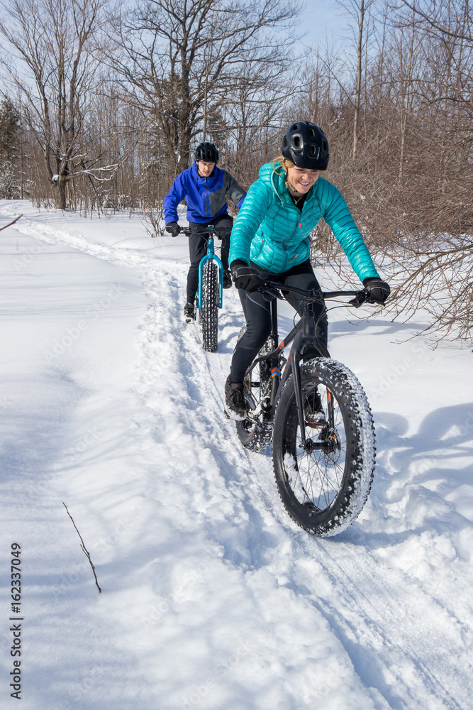 Attractive couple riding fat bikes in the snow