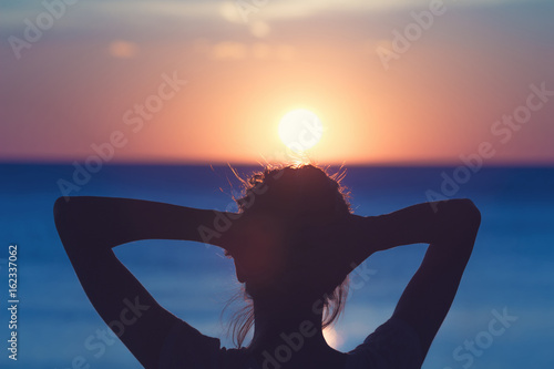 Silhouette of a girl while enjoying the sunset / sunrise at ocean / sea.