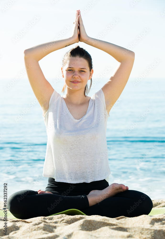 Fototapeta premium Sportswoman in white T-shirt is sitting and practicing yoga