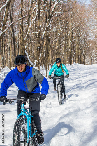 Attractive couple riding fat bikes in the snow
