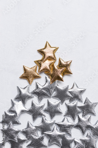 Golden and silver stars in a tree shape chtristmas tree concept on a white textured background