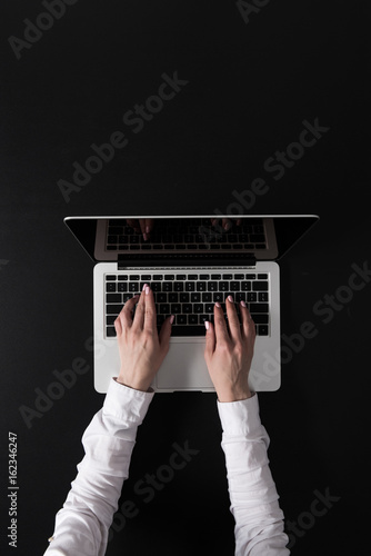 cropped shot of woman working on laptop isolated on black