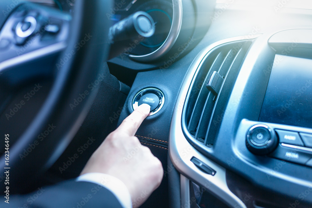 detail shot of young businessman starting engine in his car.