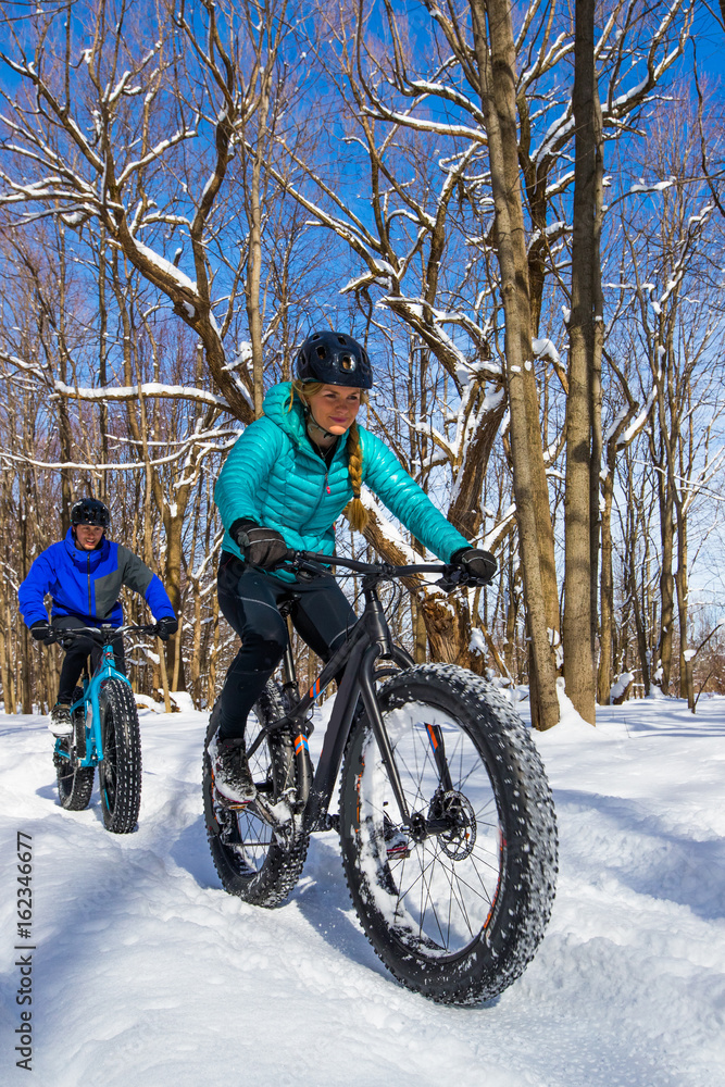 Attractive couple riding fat bikes in the snow
