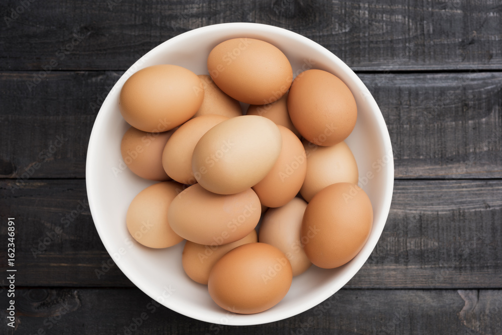 Fresh hen egg in white bowl on Black color wood table Fresh hen egg in white bowl on Black color wood table