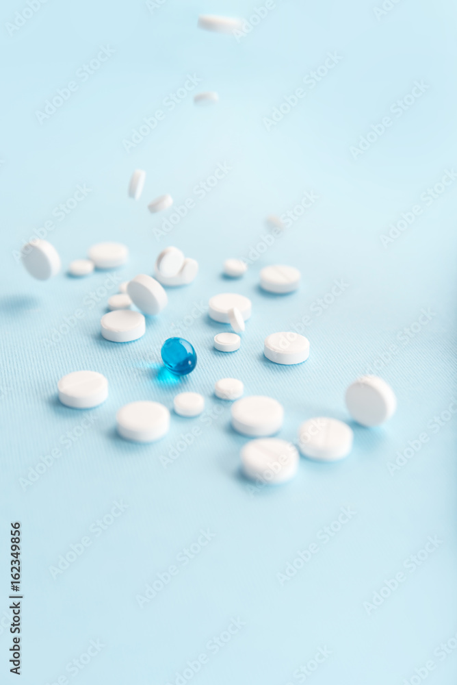 Fallen white tablets with one blue capsule isolated Fallen white tablets with one blue capsule isolated