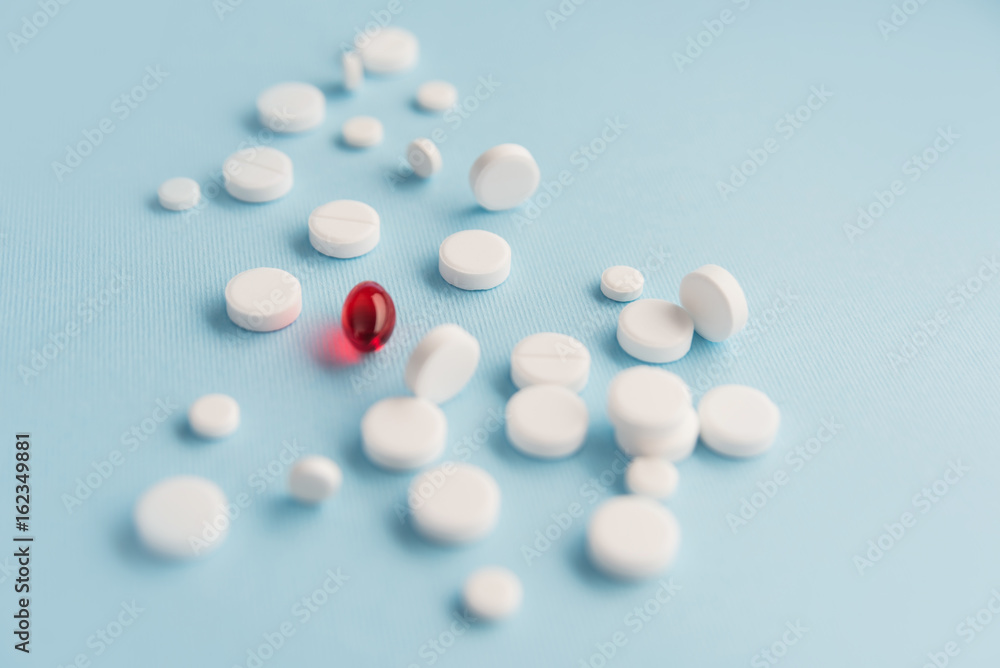 Close up of white tablets with one red capsule