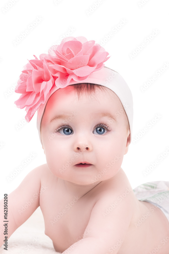 portrait of cute baby girl with pink bow flower on her head, isolated on white. adorable child with big blue eyes lying on soft blanket, studio shoot portrait of cute baby girl with pink bow flower on her head, isolated on white. adorable child with big blue eyes lying on soft blanket, studio shoot
