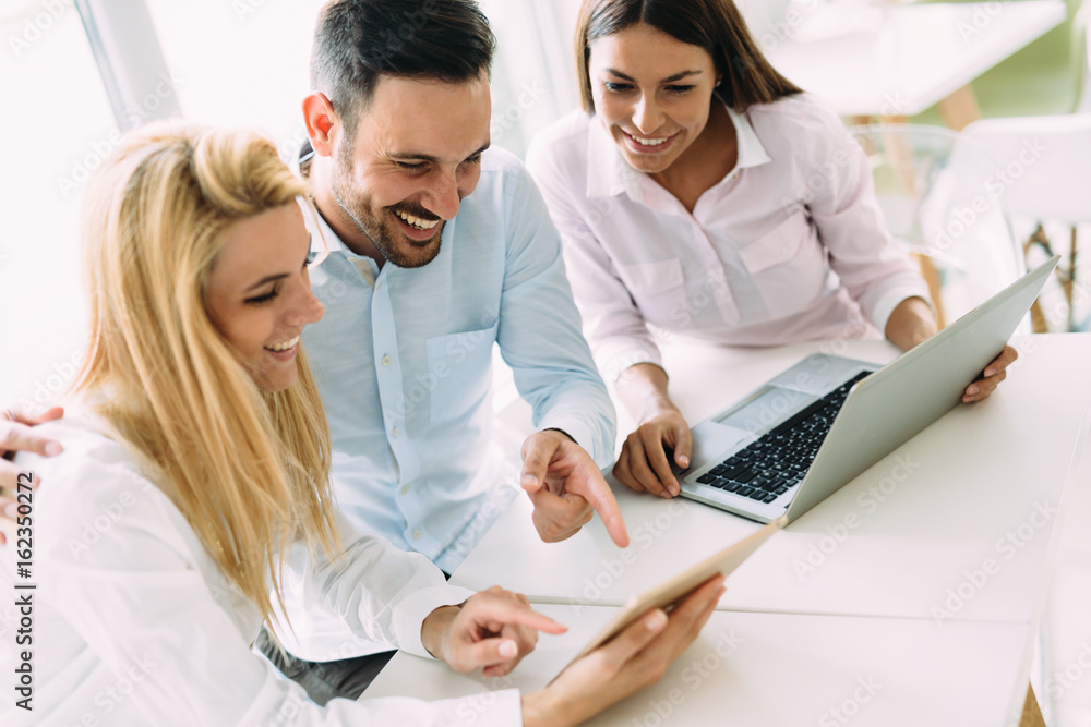 Three young smiling colleagues working together on laptop Three young smiling colleagues working together on laptop