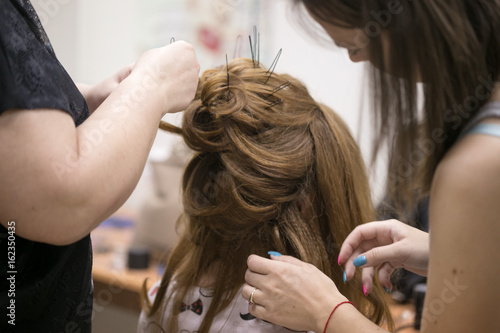 a hairdresser does a hairstyle for a girl in a hairdresser's 