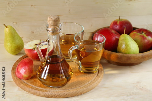 Apple cider and fruit on wooden background.