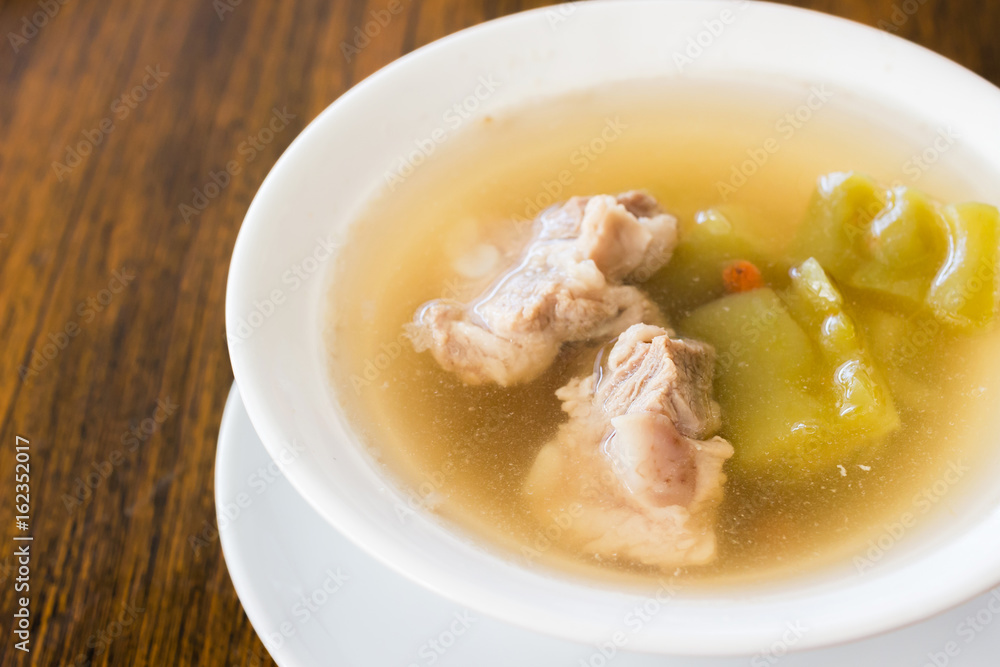 Bitter gourd soup with pork ribs in bowl on wood table Bitter gourd soup with pork ribs in bowl on wood table