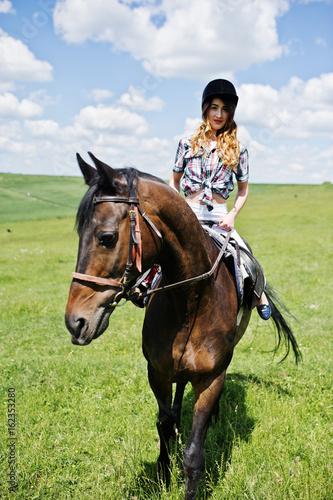 Young pretty girl riding a horse on a field at sunny day. © AS Photo Family