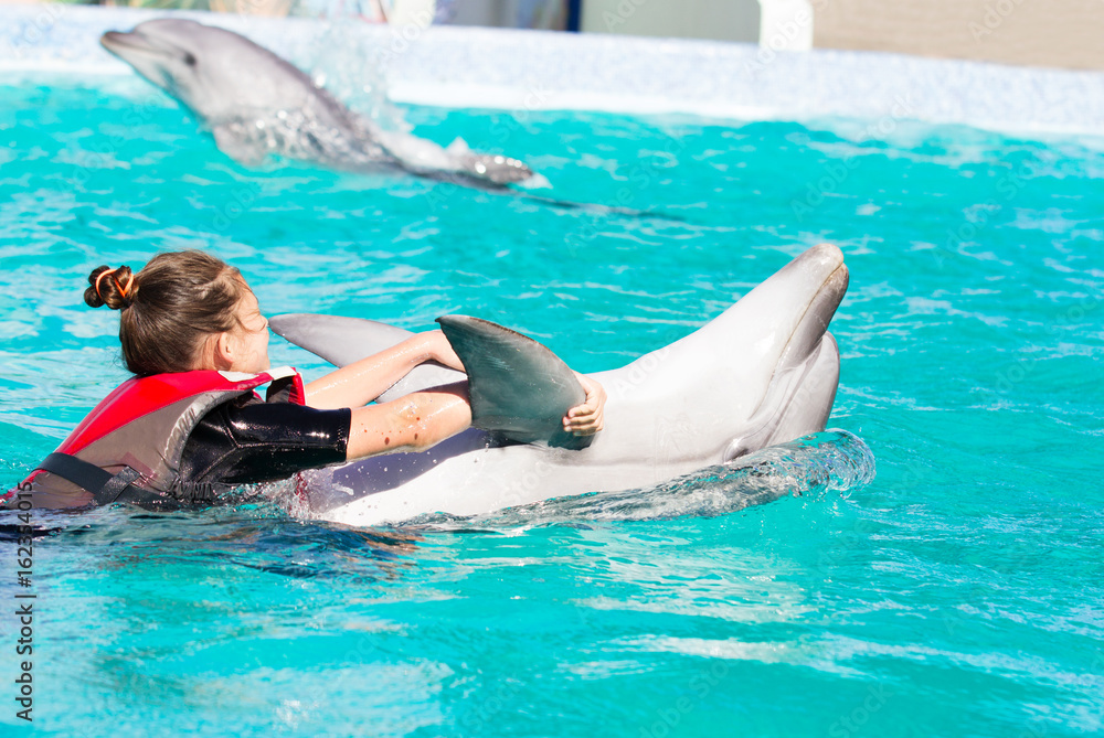 Fototapeta premium Dziewczyna i delfin pływają razem