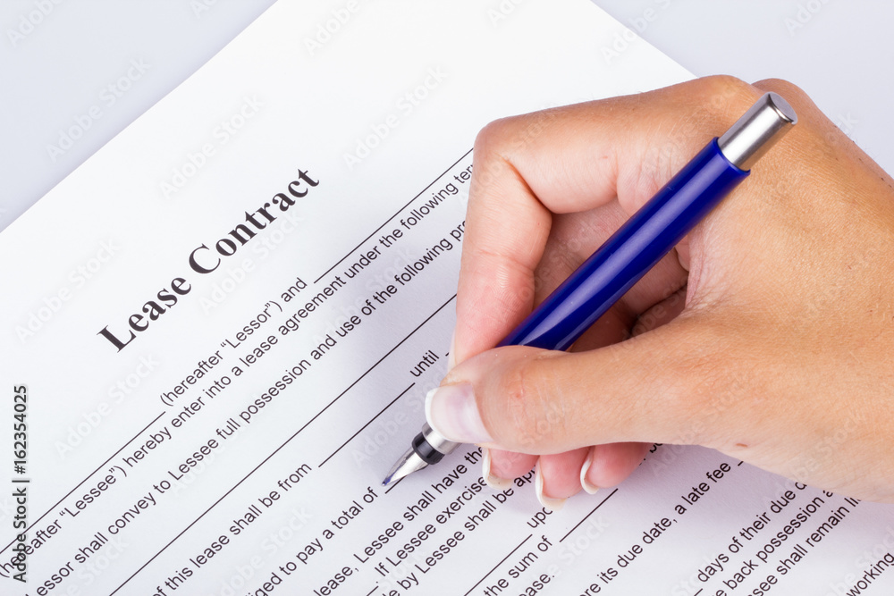 Lease Contract Overview - female hand holding a fountain pen going over the contract Lease Contract Overview - female hand holding a fountain pen going over the contract