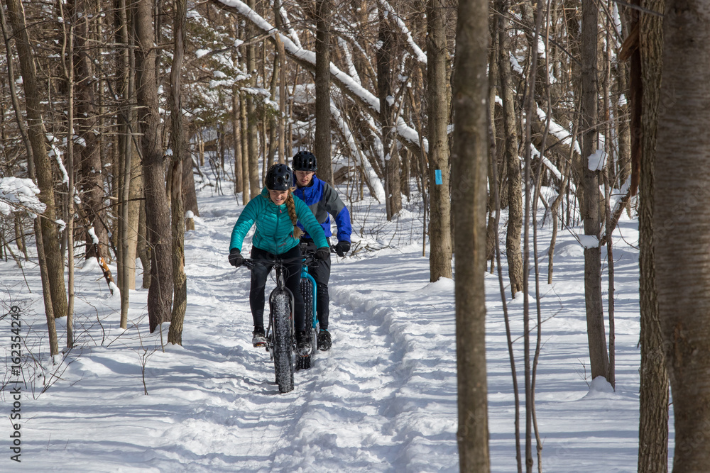 Attractive couple riding fat bikes in the snow