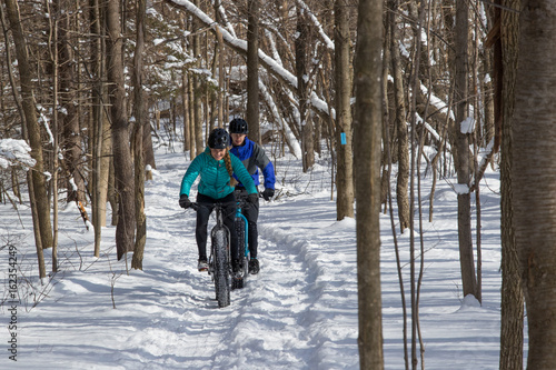 Obraz na płótnie Attractive couple riding fat bikes in the snow w salonie
