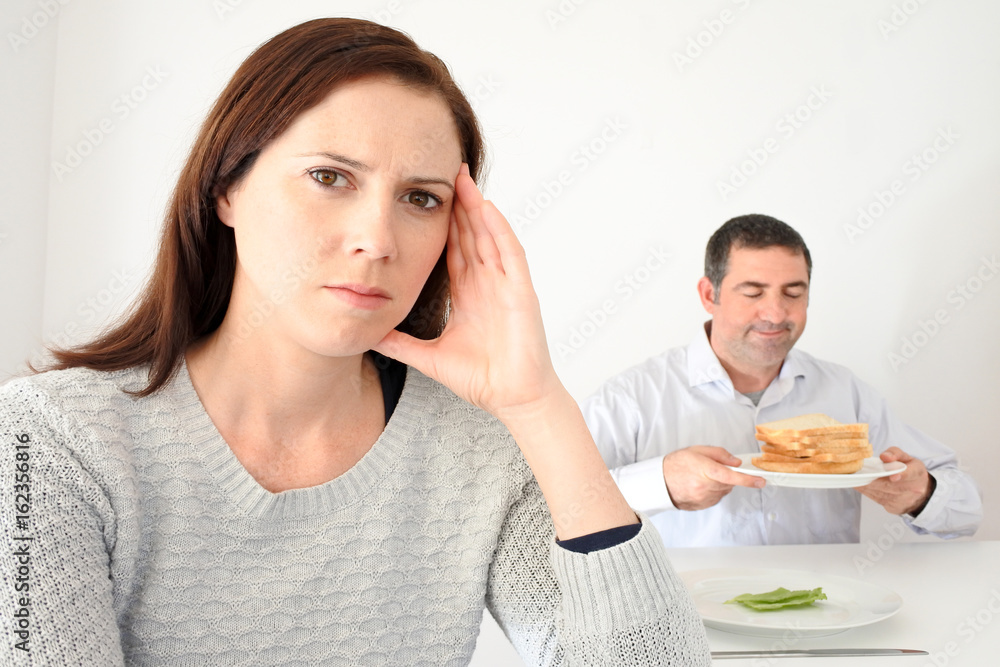 Young woman upset when her partner eat and enjoys carbohydrates Young woman upset when her partner eat and enjoys carbohydrates
