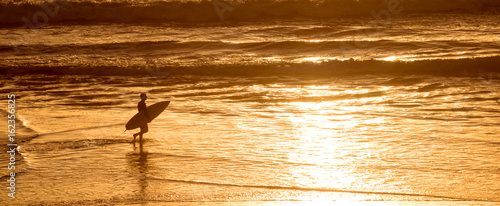 Silhouette of a surfer at sunset on the atlantic ocean in  Lacanau France, panorama and surf concept