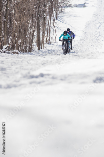 Obraz na płótnie Attractive couple riding fat bikes in the snow w salonie