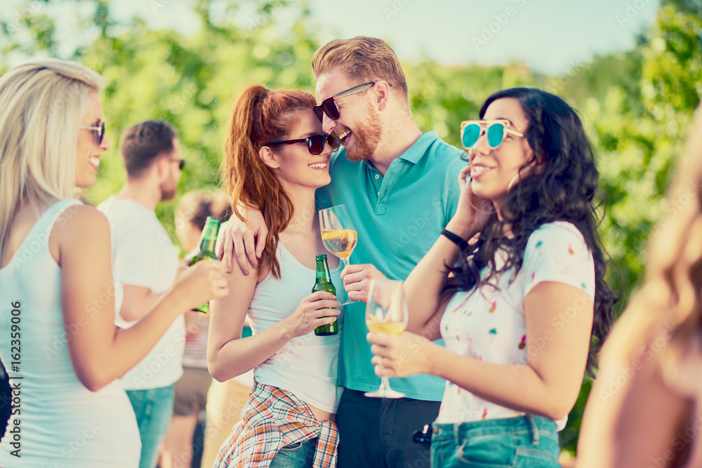 Group of best friends chatting and drinking while standing at outdoor party Group of best friends chatting and drinking while standing at outdoor party