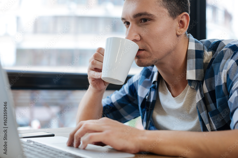 Responsible energetic guy enjoying morning coffee