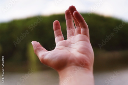 A man's hand on a blurred natural background. Photo for oktyrtki, poster or advertising banner / flyer. © vitalygrin