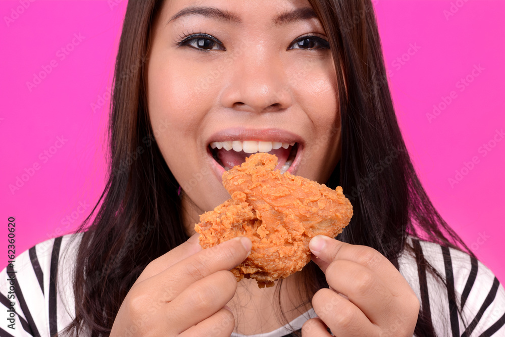 Young Asian woman eating fried chicken