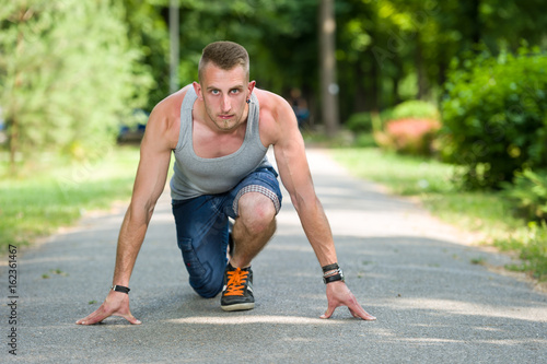 runner man in start position in a park in summer