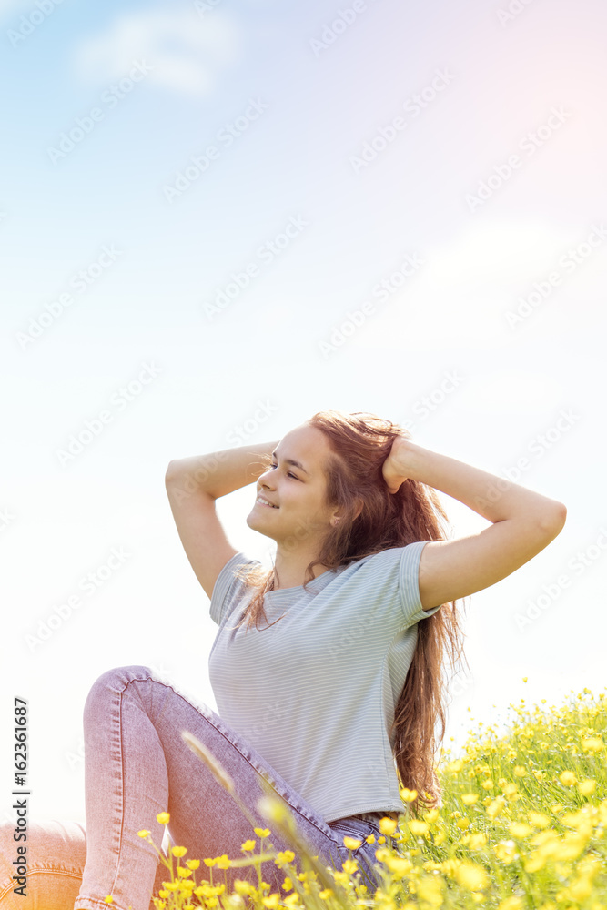 Young girl teenager on a lawn field with yellow flowers. Long chestnut hair. Sunshine, springtime, blue sky. Coloring and processing photos with soft selective focus. Shallow depth of field. Young girl teenager on a lawn field with yellow flowers. Long chestnut hair. Sunshine, springtime, blue sky. Coloring and processing photos with soft selective focus. Shallow depth of field.