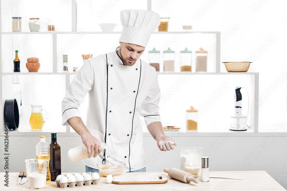 Chef in uniform makes dough in kitchen Chef in uniform makes dough in kitchen
