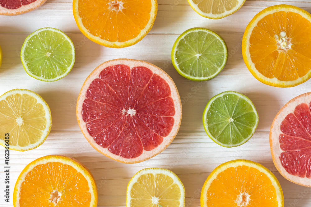 Slices of lemon, orange, lime and grapefruit on white wooden table. Pattern of food.