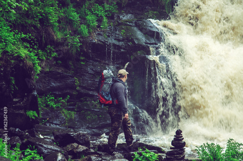 Hiker with a backpack near waterfall.
