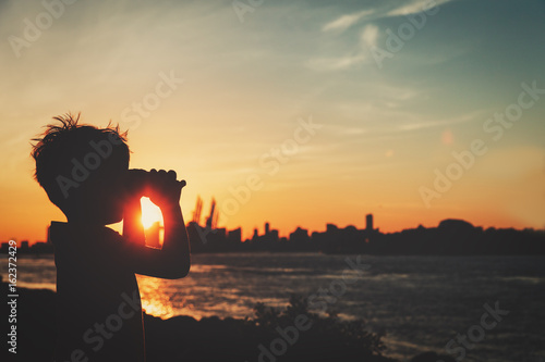 little boy looking at sunset city