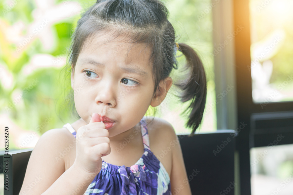 Little asian girl feeling happy while eating candy sticks Little asian girl feeling happy while eating candy sticks